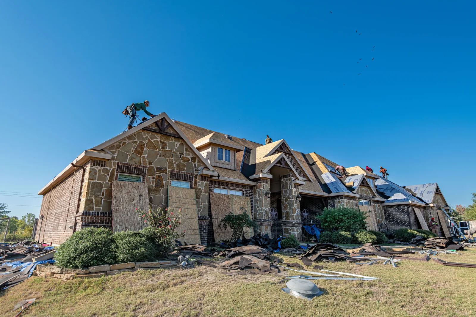 Roofing crew inspecting hail damage on a Denver home